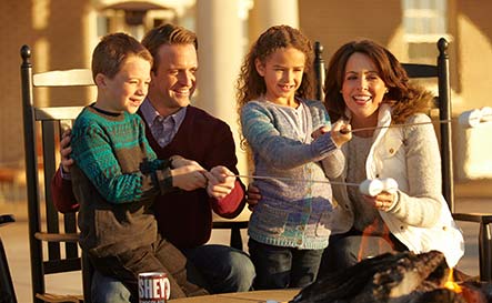 Family toasting marshmellows in a firepit on the Veranda of the hotel hershey