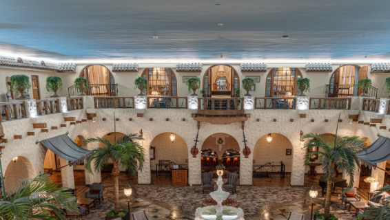 Nightime shot of Fountain Lobby in the middle of the hotel, with fountain in the middle of the room, outdoor seating, and open arcs lined on the outside of the building.