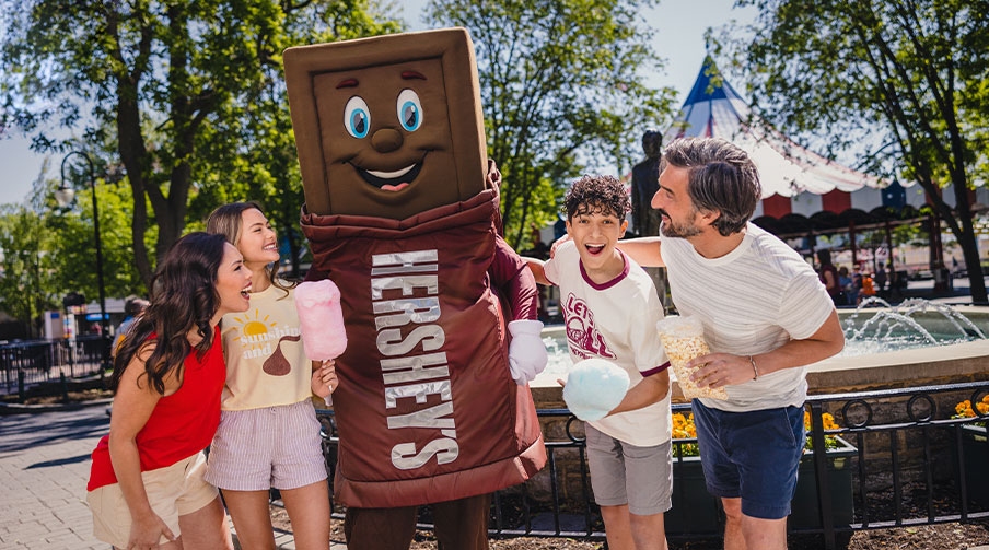 Family smiling with a Hershey Bar character at Hersheypark