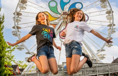 Two girls jumping for joy in front of ferris wheel at Hersheypark