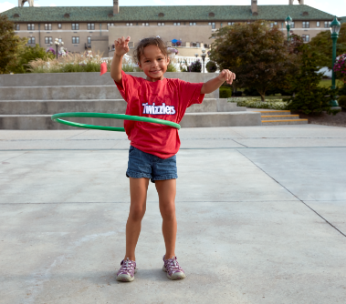 Little girl in red Twizzlers t-shirt, hoola hooping outside of the Hotel Hershey.